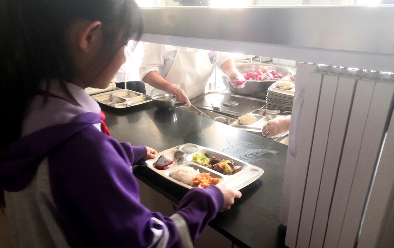 伊金霍洛旗第一小學(xué)學(xué)生正在打飯，今天的飯菜是三菜一湯外加水果，學(xué)生可以多次盛取，吃飽為止。人民網(wǎng)記者 孫博洋攝