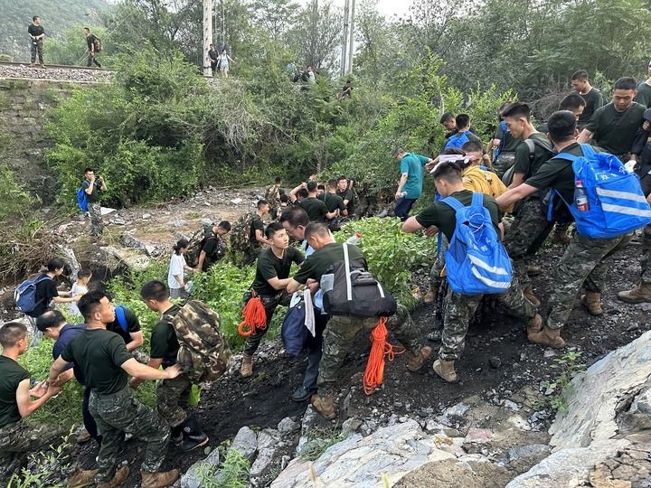 8月2日，Z180次受困列車的旅客在武警北京總隊(duì)機(jī)動(dòng)第三支隊(duì)官兵的幫助下徒步前往轉(zhuǎn)運(yùn)客車（手機(jī)照片）。新華社記者 王艷剛 攝
