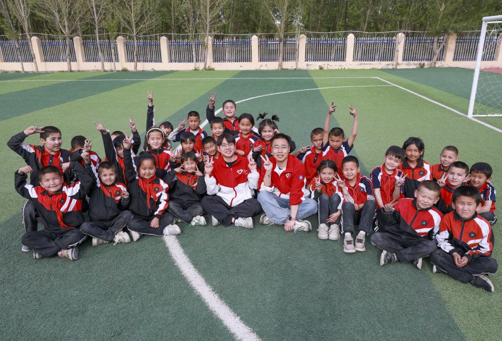 4月23日，在新疆克州阿圖什市哈拉峻鄉(xiāng)謝依特小學，支教教師王俊文（中左）、李軻凡（中右）和學生在一起。