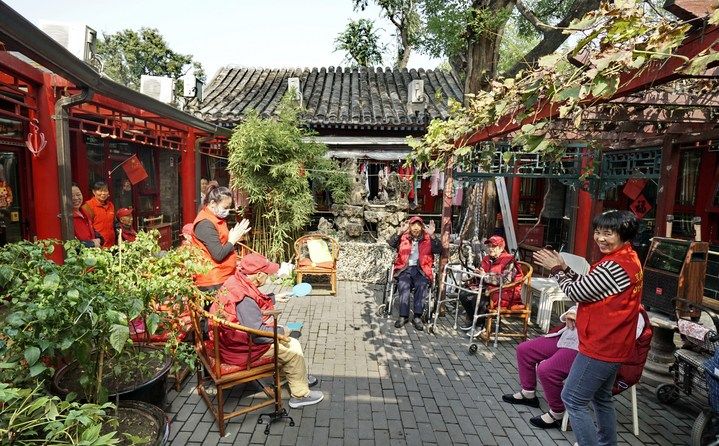 2024年10月12日，鐘樓灣胡同的老年人在社區(qū)內(nèi)的四合院養(yǎng)老驛站休閑。2017年起，北京市先后開(kāi)展了兩輪背街小巷環(huán)境整治提升行動(dòng)，完整保留了中軸線生活建筑群的歷史信息，并根據(jù)居民的生活和居住方式進(jìn)行適配化的更新和改造，極大地改善了生活環(huán)境。2023年鐘樓灣胡同被評(píng)為“北京最美街巷”。